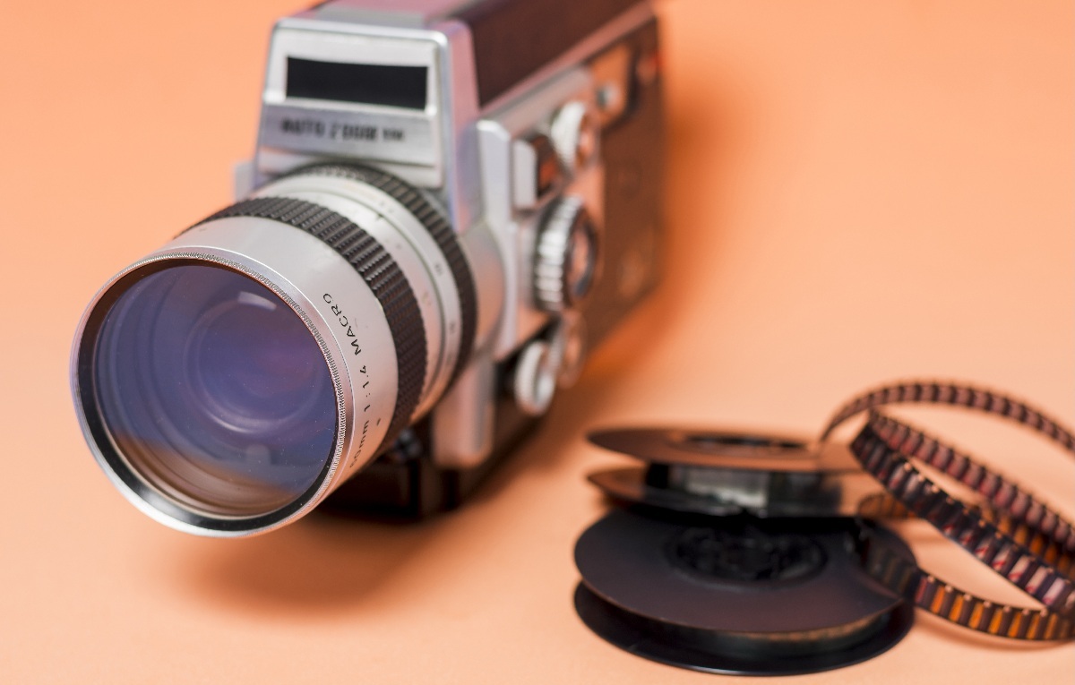 Stara kamera z taśmami filmowymi obok na pomarańczowym tle